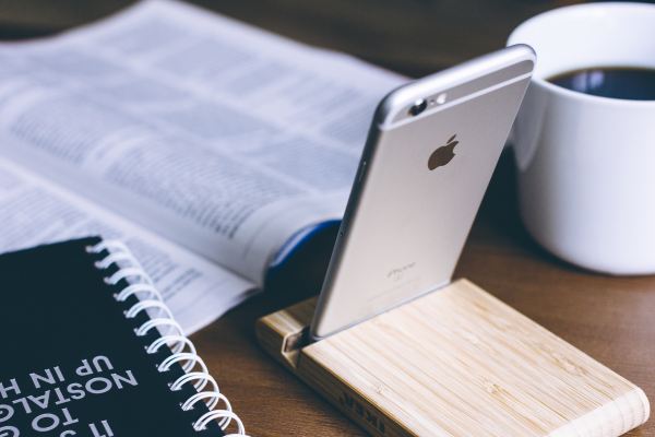 Smartphone on stand in front of textbook and coffee