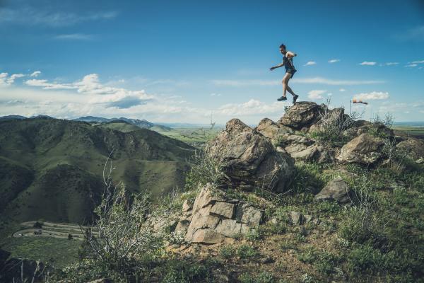 Man jumping from a rock on mountain in daylight